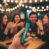 AirsPops ONE USE 6ml disposable vape held in hand at a social evening setting with friends in the background