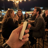 Person holding Matte White AirsPops Pro II in a social nightlife setting